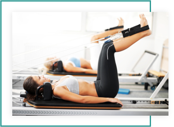 Two women are doing exercises on a pilates machine.